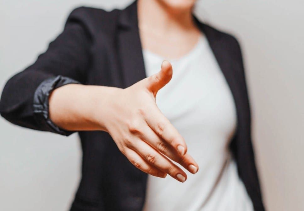 Femme en blazer noir qui tend la main pour une poignée de main