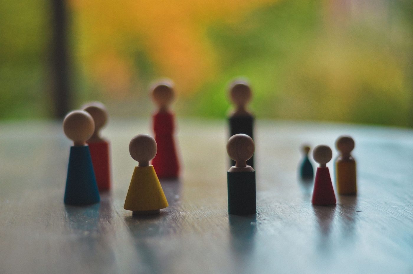 Figurines en bois colorées, bleues, rouges, jaunes et noires, disposées sur une table
