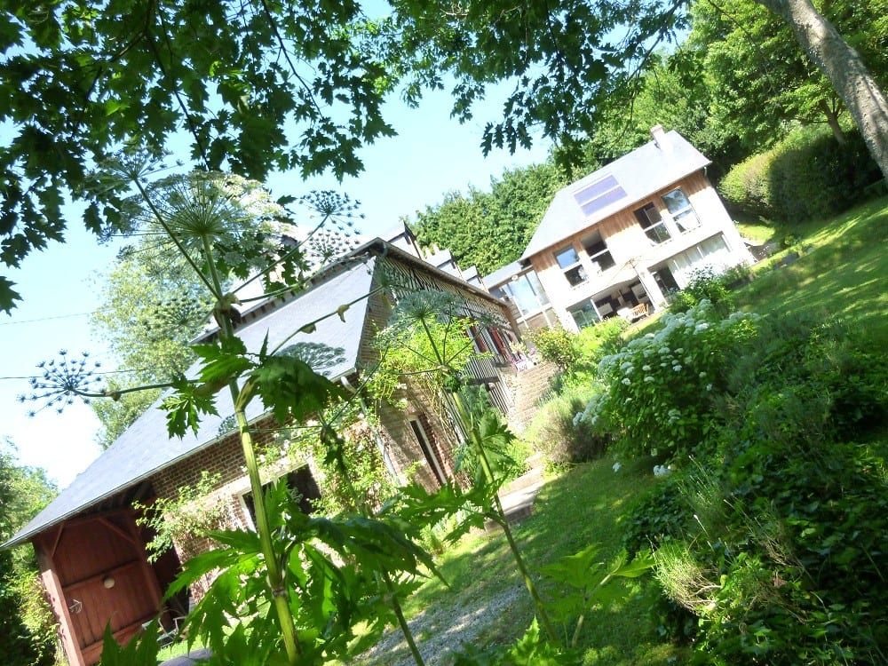 La maison d’hôtes à Courtonne-la-Meurdrac, en briques et ardoise, vue à travers des ombellifères en fleur